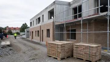 Tegelpallar och byggställning framför en ofärdig byggnad.