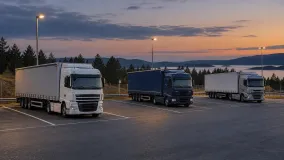 Lastbilar parkerade på en belyst uppställningsplats längs en större väg